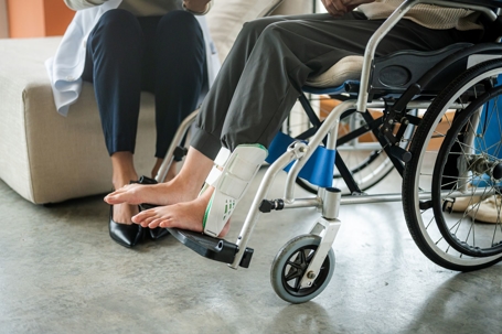 Person with an injured ankle sits in a wheelchair