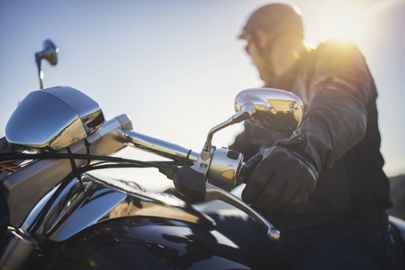 Motorcycle rider stares off toward the sun